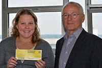 Jürgen Heinrich von der Westfälisch Lippische Universitätsgesellschaft (WLUg) übergibt Studentin Marina Ragusin aus Brasilien ein Ticket für das Campus Festival. Foto: Universität Bielefeld