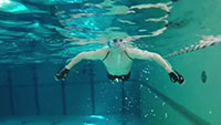 Brustschwimmer im Schwimmbecken der Universität Bielefeld trainiert mit Handschuhen, mit denen die Handbewegungen unter Wasser in Klang umgewandelt werden. Foto: CITEC/ Universität Bielefeld
