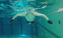 Bild: Brustschwimmer im Schwimmbecken der Universität Bielefeld trainiert mit Handschuhen