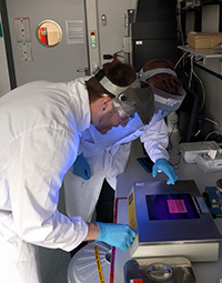 Bild: Yannic Kerkhoff und Daniel Bergen identifizieren mit UV-Licht DNA-Fragmente. Foto: Universität Bielefeld 