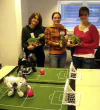 Die Roboter in der Technischen Fakultät begeisterten die Schülerinnen (v.l.): Sara Biller (Deutsche Schule Shanghai), Sabrina Möllmann (19 Jahre) und Anjuli Meier (16) mit Roboterdinosaurier „Pleo“; im Vordergrund Roboterhund „Ai-bo“ von Sony