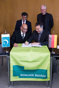 Bild: Professor Dr. Mujahid Kamran und Rektor Gerhard Sagerer (sitzend v.l.) unterzeichnen die Kooperationsvereinbarung. Im Hintergrund: Prof. Dr. Muhammad Zakria Zakar