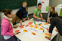 Bild: Das ist Peer Assisted Learning: Studierende arbeiten gemeinsam mit einem älteren studentischen Begleiter die Inhalte einer Vorlesung auf. Foto: Universität Bielefeld