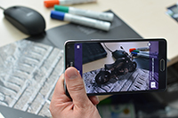 Bild: Mit speziellen Apps – hier von der Bielefelder Firma Raumtänzer – lassen sich aus Print-medien Extra-Informationen als erweiterte Realität auf dem Smartphone darstellen. So wirkt es