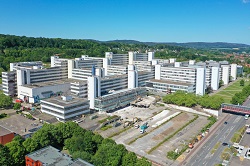 Die Luftaufnahme zeigt das Hauptgebäude der Universität Bielefeld aus östlicher Richtung. Im Vordergrund sind der ehemalige Frauenparkplatz sowie die bereits begonnenen Abrissarbeiten im Bereich der Mensa zu erkennen.
