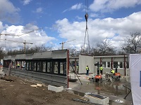 Bild: Auf der Baustelle des Gebäudes R.2 werden erste Außenwandelemente montiert. 