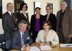 Bild: Dr. Jens Mogens Holm und Prof. Dr. Isabell Diehm bei der Vertragunterzeichnung und dahinter (v.l.): Dr. Frank Strikker (Projektleiter des weiterbildenden Fernstudiums "Coaching & Moderation" im ZWW)