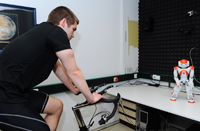 Bild: Roboter Nao leitete jeden Probanden täglich für eine Stunde beim Spinning auf dem Indoor-Fahrrad an. Foto: Deutsches Zentrum für Luft- und Raumfahrt 